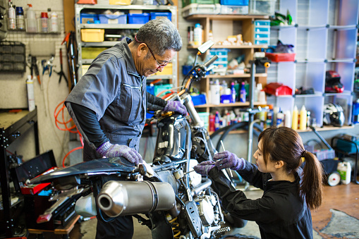 Father teaching daughter how to repair a motorcycle.