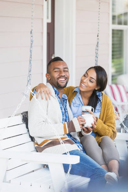 istock Young mixed race couple drinking coffee on porch swing 821198892