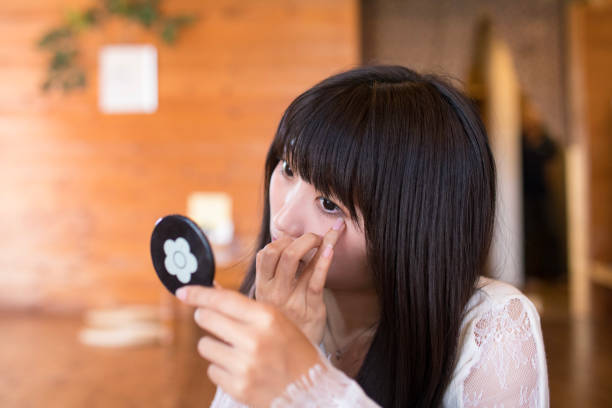 Beautiful young woman looking at her reflection in a circular mirror.