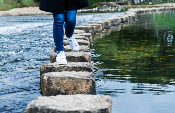 istock Woman crossing stepping stones on a river 821249928