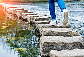 Woman crossing stepping stones on a river