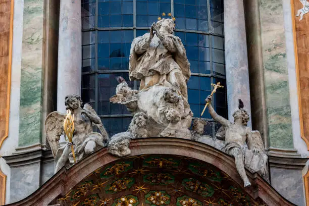 A statue of a saint and two angels on the facade of Asamkirche church historical building in downtown Munich, Bavaria, Germany