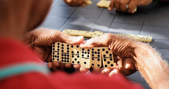 Retired people, seniors and free time. Old latino men having fun and playing game of domino in Cuba.