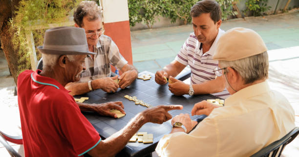 активный выход на пенсию счастливые старые друзья, играющие domino игры - домино стоковые фото и изображения