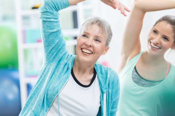 istock Senior woman and classmate stretch during yoga class 821268502