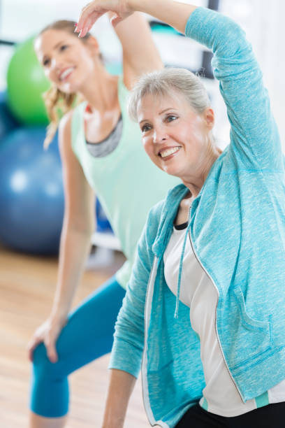 istock Senior woman lunges and stretches torso in gym class 821268524