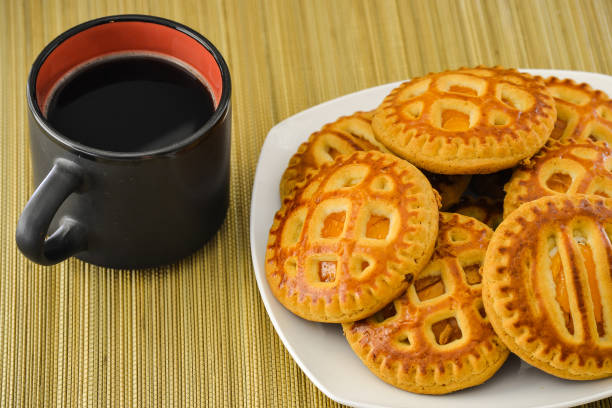 cookies auf einen teller und eine tasse kaffee in einem schwarzen becher. ansicht von oben - biscotti coffee cappuccino latté stock-fotos und bilder