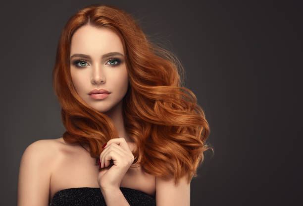 rudowłosa kobieta z obszerną, błyszczącą i kręconą fryzurą. latające włosy. - hairstyle long hair curly hair women zdjęcia i obrazy z banku zdjęć