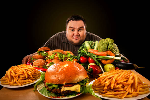 Diet fat man makes choice between healthy and unhealthy food. stock photo
