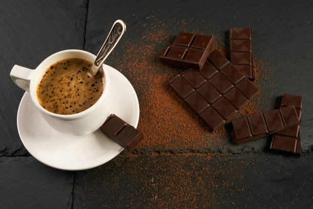 istock Black coffee with creamy foam, chocolate pieces and cocoa powder on black stone kitchen table. 821312734