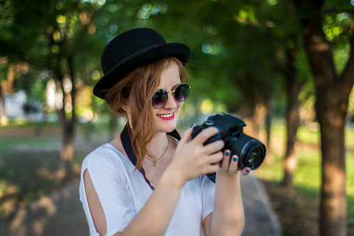 Portrait of smiling young woman holding a digital camera. Horizontal composition. Image taken with Nikon D800 and developed from Raw format.
