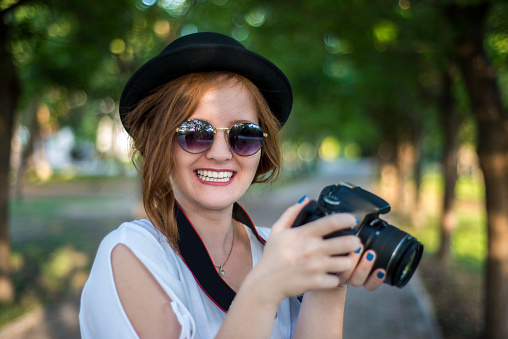 Portrait of happy young woman looking at camera by laughing holding a digital camera. Horizontal composition. Image taken with Nikon D800 and developed from Raw format.