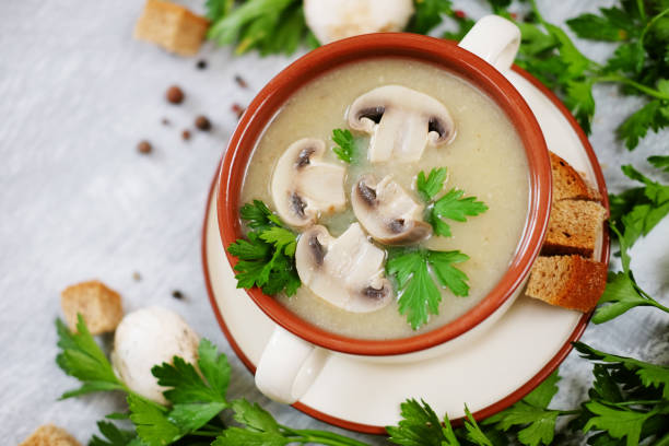istock Fresh mashed mushroom soup decorated with green parsley, bread croutons and pepper on grey background 821353366