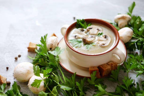 istock Fresh mashed mushroom soup decorated with green parsley, bread croutons and pepper on grey background 821353388