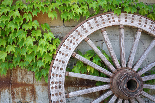 Old wooden wagon wheel hanging against a stone wall