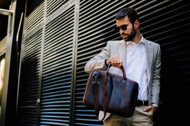 istock Handsome young businessman at black wall 821368884