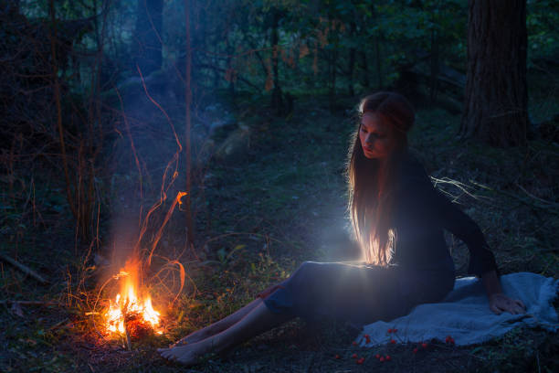 istock beautiful witch looking at the fire in the forest 821369380