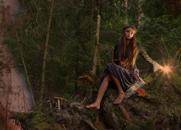 istock Beautiful witch sitting on a tree trunk in the forest 821369410