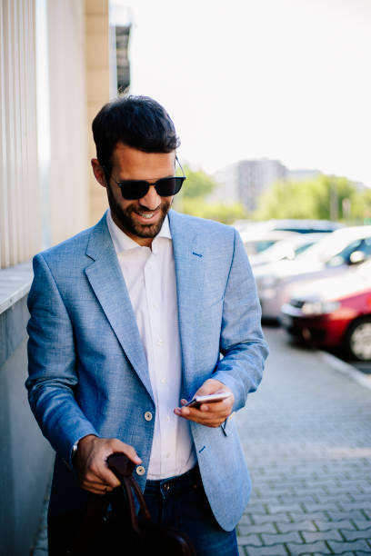istock Smiling businessman typing message on smartphone outdoors 821385750