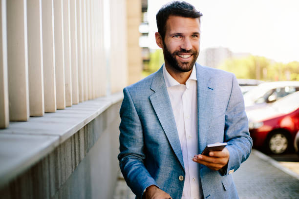 istock Handsome smilling young man at parking using smartphone 821385924