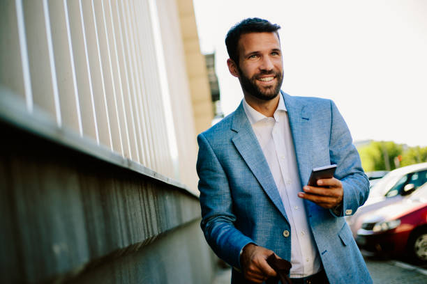 istock Handsome young businessman using smartphone at parking 821386356