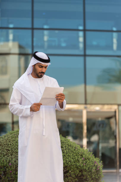 istock Arab Businessman Reviewing Document Outside Modern Office Building, Dubai 821407002