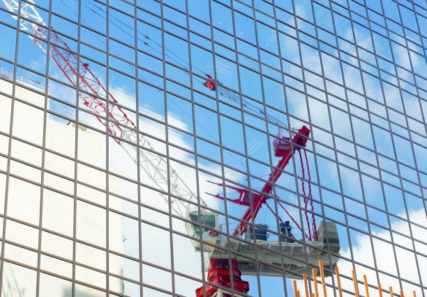 Urban development: hong kong tower Crane and clouds in the construction site with the reflection in mirror of nearby glass building