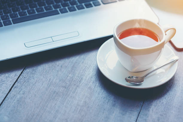 istock Hot cup of tea and laptop on wood table 821419126