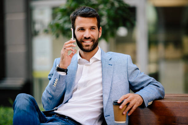 istock Handsome smiling man using smartphone and drinking coffee outdoors 821419324