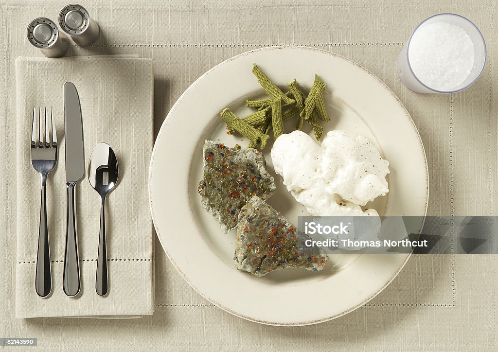 place setting with food and drink meat - cement seasoning - crushed glass potatoes - spray insulation green beans - garden gloves milk - rock salt Artificial Stock Photo