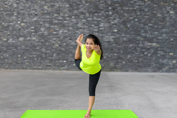 Healthy lifestyle. Happy woman smiling and doing yoga in standing half bow pose or Utthita Ardha Dhanurasana pose at studio. Fitness for relaxation and stretching. Isolated on white background.