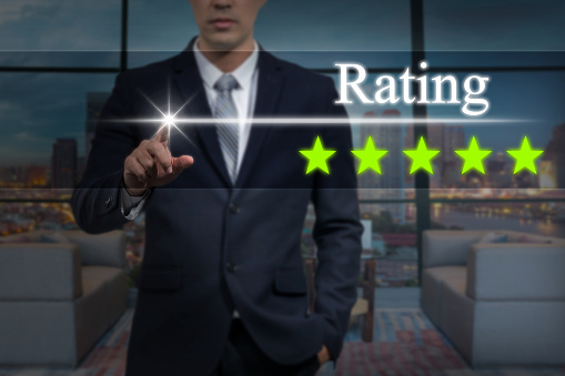 Businessman pointing five star button to increase rating of hotel over blurred of interior lobby background, business evaluation concept, Increase rating
