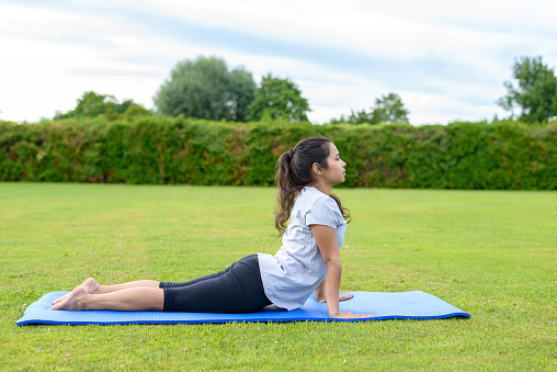 Portrait of teenage girl practising yoga on mat outdoors, Cobra Position