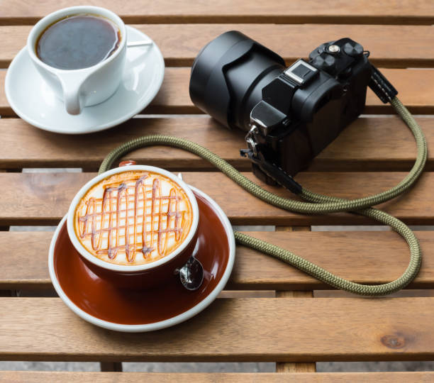 two coffee cups and a camera on a wood table