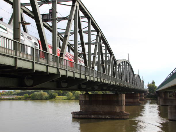 istock Old Green Metal Railroad Bridge with Red Train Crossing River 821454806