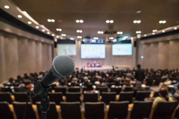 Microphone over the Abstract blurred photo of conference hall or seminar room with attendee background, Business meeting concept stock photo