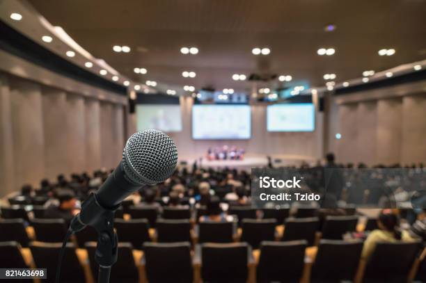 Microphone Over The Abstract Blurred Photo Of Conference Hall Or Seminar Room With Attendee Background Business Meeting Concept Stock Photo - Download Image Now