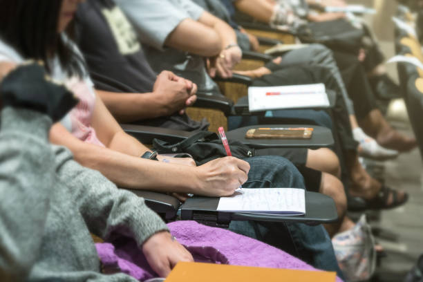 close up shot of woman hand writing on the paper at the table in the conference hall or seminar meeting, business and education concept - business seminar writing women imagens e fotografias de stock