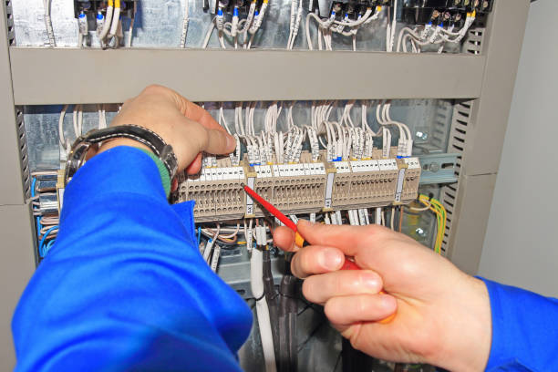 istock Engineer clamps electrical wires into terminals of electrical cabinet with screwdriver. 821467098