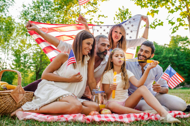istock Happy family playing soap bubbles in park while holding Usa flags 821486888
