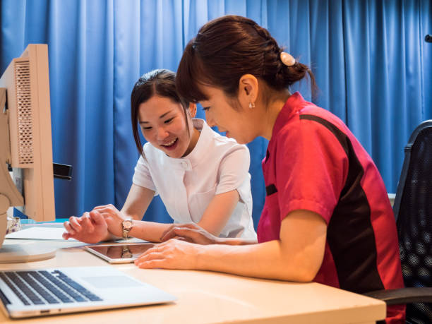 日本の看護師がタブレットから patiient データをチェック - patiient ストックフォトと画像