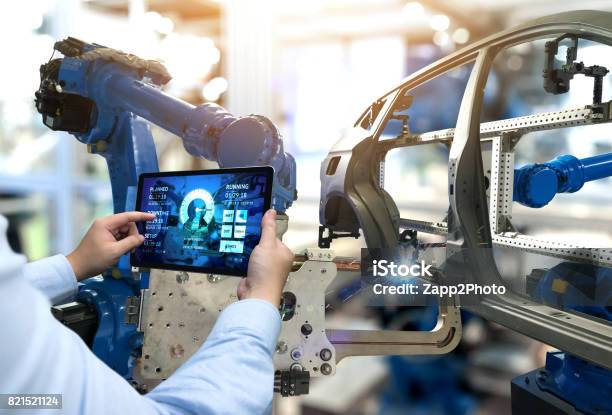 Engineer Hand Using Tablet With Machine Real Time Monitoring System Software Automation Robot Arm Machine In Smart Factory Automotive Industrial Industry 4th Iot Digital Manufacturing Operation Stock Photo - Download Image Now