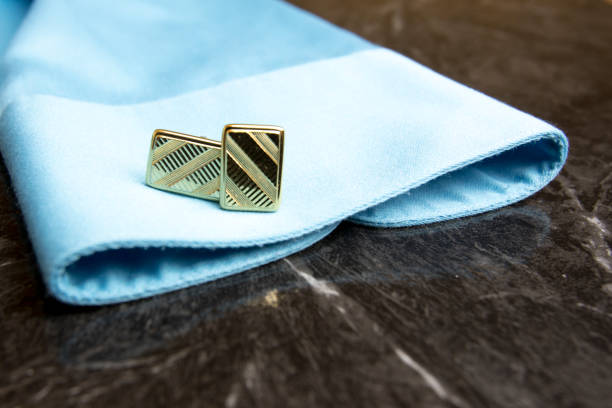 Pair of gold cuff links on blue mens dress shirt.