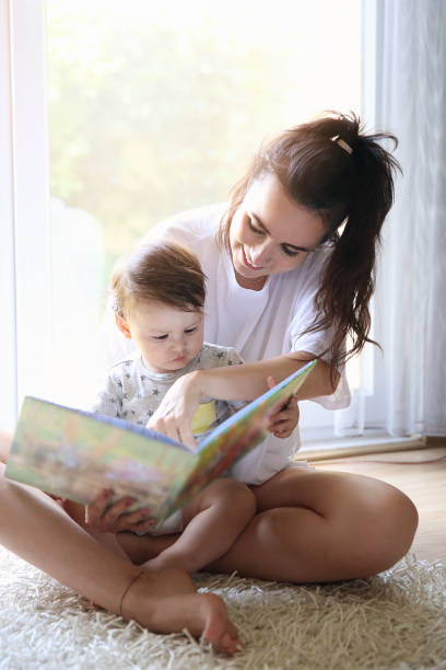 istock Mother reading a book to her baby on carpet 821533038