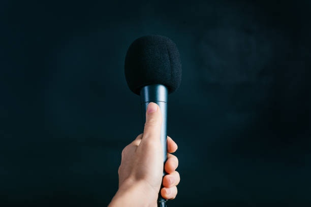 istock Female hand holding microphone on black background 821536278
