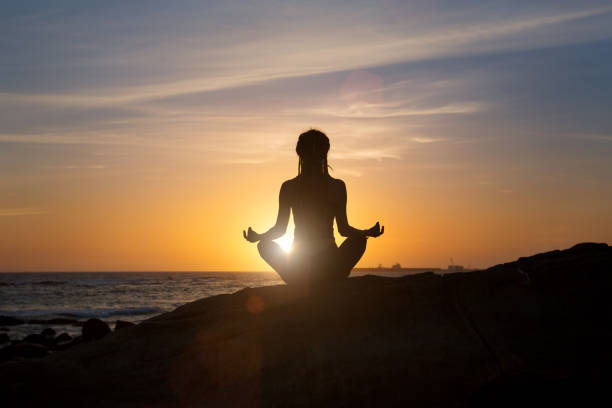 istock Silhouette young woman practicing yoga on ocean beach at sunset 821536860