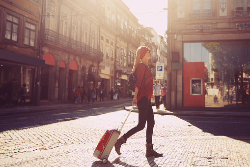 Woman tourist walking with suitcase on  European city street, tourism in Europe, travel background