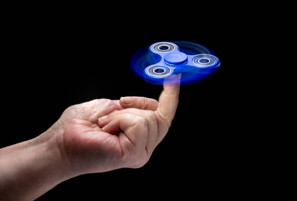 istock Fidget Spinner Toy In Human Left Hand Isolated On Black Background. 821537642