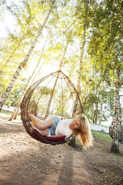 istock Joyful young woman having fun on a hanging chair 821544796