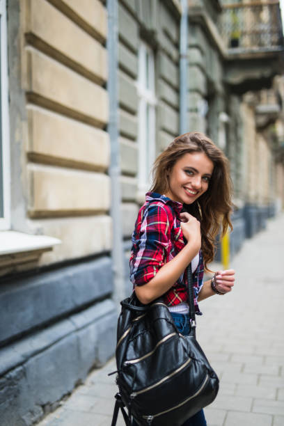 istock Happy charming young woman with backpack walking in the city back view 821561500